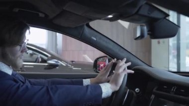 Ellerini direksiyona holding iş elbiseli sakallı işadamı kapatın. Kendine güvenen adam motor Show'da otomobil incelenmesi. Konsept otomobil, otomatik iş satın alma