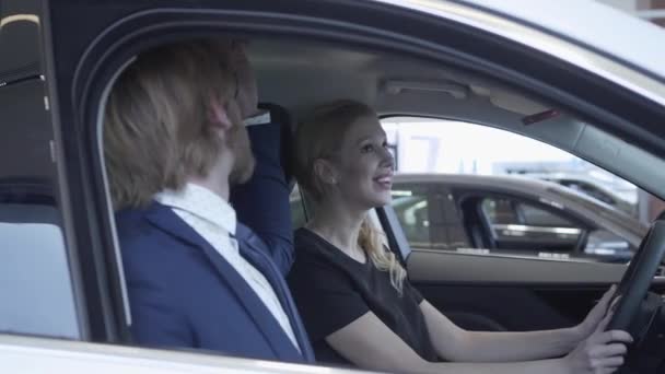 Ein glückliches erfolgreiches Paar, das im Fahrgastraum des neuen Fahrzeugs sitzt, inspiziert den Innenraum des neu gekauften Autos beim Händler. Autohaus. — Stockvideo