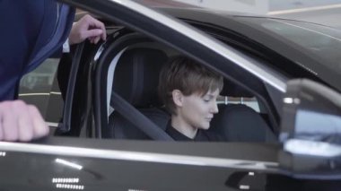 Yolcu bölmesi araç lastik yeni aracın içinde oturan bir genç bayan. Professioal satıcı müşteri danışmanlık takım elbiseli. Araba Bayilik.
