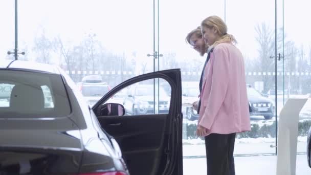 Casal feliz escolhe um novo veículo em uma concessionária de carros. Sala de exposições do carro . — Vídeo de Stock