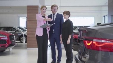 Pazarlamacı içinde pembe ceket müşteriler çift araba hakkında danışmanlık. İşadamı ve eşi araç seçimi. Konsept otomobil, otomatik iş satın alma