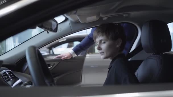 Gelukkig schattig jong meisje in de passagiersruimte van de nieuwe auto. Succesvolle vrouw onderzoekt nieuwe auto. Automobielbedrijf. — Stockvideo