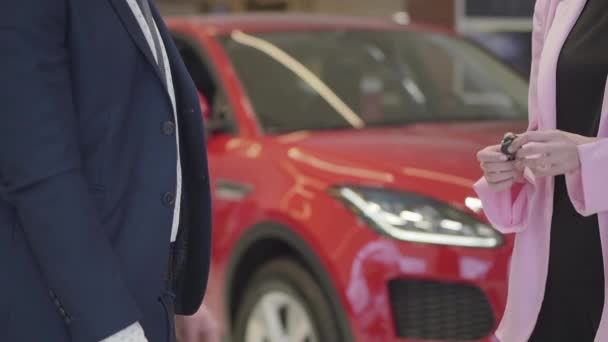 Venditore non riconosciuto invia le chiavi per la nuova auto al nuovo proprietario. Un uomo in giacca e cravatta ha stipulato un accordo per comprare un nuovo veicolo. showroom auto . — Video Stock