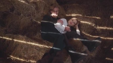 Genç bir çift sarılma saman ahırda yatıyor. Mutlu gülümseyen erkek ve kız birlikte vakit geçirmek. Ağır çekim.