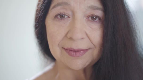 Retrato de atraente triste mulher idosa infeliz com lindo longo cabelo escuro olhando em câmera chorando, com os olhos cheios de lágrimas de perto. Antecedentes desfocados — Vídeo de Stock