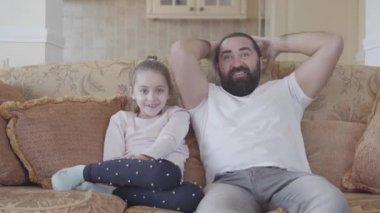 Sevimli küçük kızı komik babasıyla rahat oturma odasında büyük duygularla TV'de ilginç film seyretme