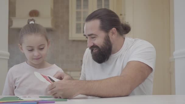 Skäggiga pappa och en vacker liten dotter måla med flamasters som sitter vid ett bord en dag. Tidsfördriv far och dotter tillsammans. Far och dotter relation. En lycklig familj. — Stockvideo