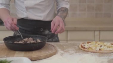 Tanınmayan adam taze kavrulmuş et tava pizza üzerinde temel koyarak kapatın. Yiyecek hazırlama kavramı. Sağ ve sol kamera taşır