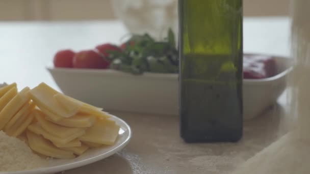 靠近桌子上的比萨饼的近景。一束面粉倒在橄榄油瓶、西红柿和奶酪附近的桌子表面。食品制备概念。相机向右和向左移动 — 图库视频影像