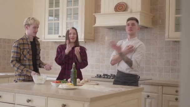 Une jeune pizzeria et ses amis jonglent avec des boules de pâte dans la cuisine. Art de la cuisine pizza — Video