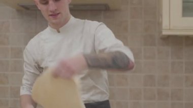 İplik ve disk pizza hamur evde mutfak savurma Şef üniformalı genç bir adam. Profesyonel oyuncu pizza yapma. Yiyecek hazırlama kavramı