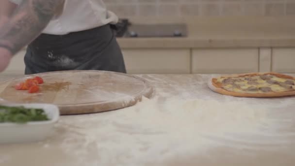 Felismerhetetlen ember vágás paradicsom cherry, az ő pizzát feküdt az asztalon közelről. Fogalma az élelmiszer-készítmény. Kamera mozog jobbra és balra — Stock videók