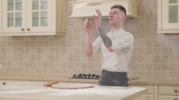 Cocinero profesional girando y lanzando masa de pizza en el aire con dos manos en la cocina . — Vídeos de Stock