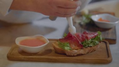Restoranda yemek roka ve tuzlanmış somon sandviç kadar yakın. Elleri sunumu için lezzetli yemekler ahşap tahta üzerinde yapma Şef. Krem üstüne koyarak Cook