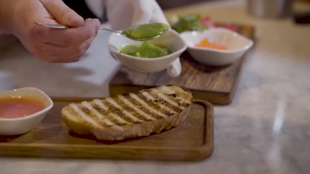 Restoranda yemek sandviç roka ile yakın. Elleri sunumu için lezzetli yemekler ahşap tahta üzerinde yapma Şef. Roka ekmek somun maşa kullanarak koyarak Cook — Stok video