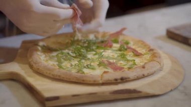 El ahşap bir gemide yalan bir pizza domuz pastırması parçaları koyarak pişirin. Pizza pişirme.