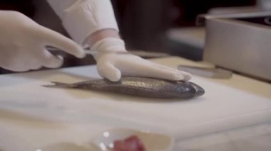 Lastik eldiven elinde Şef kesme tahtası üzerinde çiğ balık hazırlamak. Eller fileto ayrılması kemik üzerinden kontrol. Modern Restoran, deniz ürünleri gıda hazırlanmasında