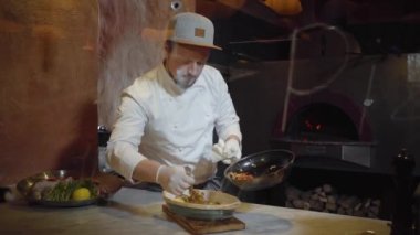 Şef küçük parçalar kesilerek koyarak beyaz üniformalı mutfakta derin tabak içinde yalan pişmiş balık sebze buğulama. İmza ile cam arkasında modern restoran gıda hazırlanmasında