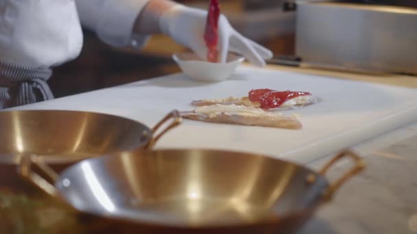 Las manos del chef preparan filete de pescado sobre tabla de cortar. Cocine poniendo salmón salado sobre queso crema sobre filetes de pescado. Preparación de alimentos en restaurante moderno, comida de mar — Vídeo de stock