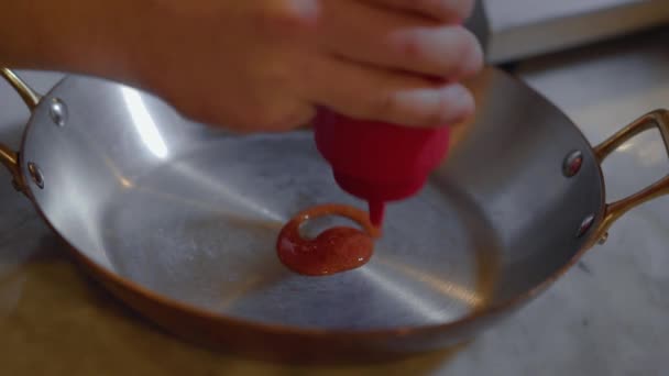 Close-up of the hands of an unrecognized cook pouring tomato sauce on the griddle. Gourmet cooking concept. — Stock Video