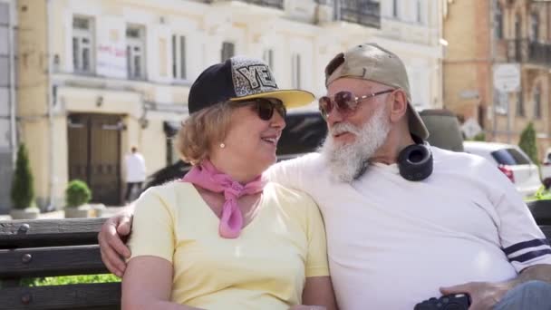 Портрет счастливых стильных стариков, отдыхающих на скамейке в городе — стоковое видео