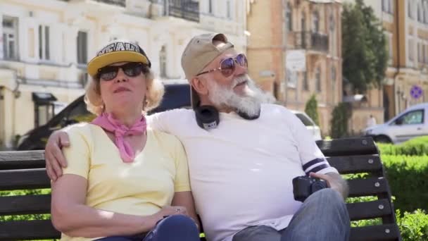 Porträt fröhlicher, stilvoller alter Menschen, die es sich auf der Bank in der Stadt gemütlich machen — Stockvideo