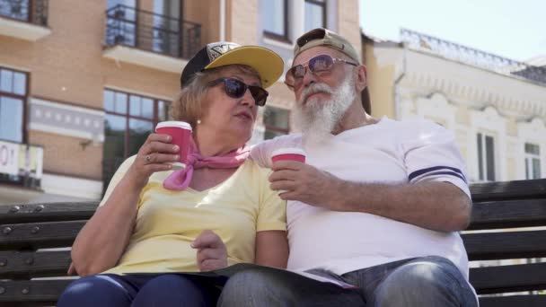 Портрет стильных стариков, пьющих кофе и отдыхающих на скамейке в городе — стоковое видео