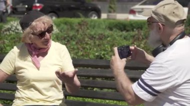 Şık Olgun çift parkta bankta oturmuş kamera fotoğrafları bakmak