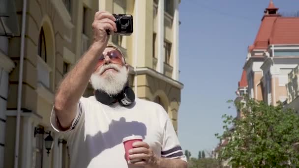 Portrait de l'homme âgé moderne prendre des photos des sites touristiques de la ville à pied seul — Video