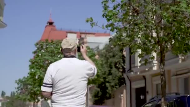 Портрет красивого пожилого мужчины прогуливается по городу и фотографирует — стоковое видео