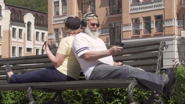 Elegante pareja de ancianos que se relajan en el banco de la ciudad — Vídeo de stock