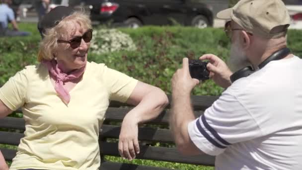 Älterer Mann fotografiert seine stilvolle schöne Frau auf der Parkbank — Stockvideo