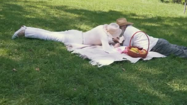 Seniorenpaar entspannt sich an Decke im Park und füttert sich gegenseitig Marshmallows — Stockvideo
