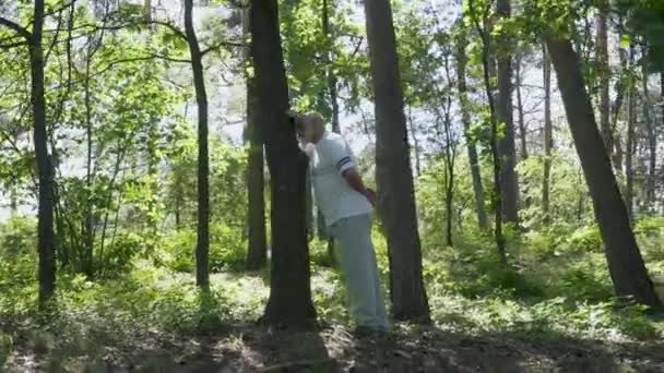 Hombre mayor apoyado en tronco de árbol — Vídeo de stock
