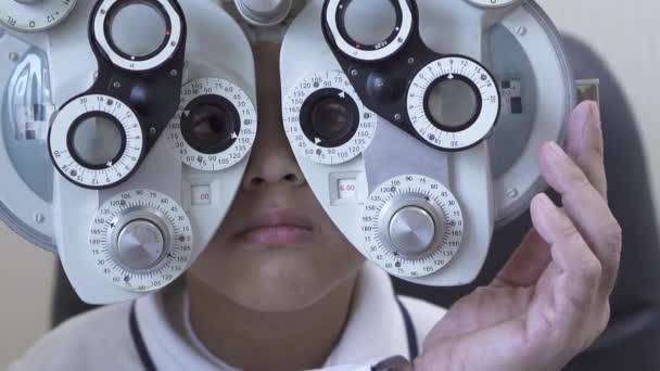 男の子 phoropter を使用して検眼医眼科医で診察をクローズ アップ。Phoropter の十代の混血少年の 1 つ目のガラスを変更する医者の手。スローモーション — ストック動画