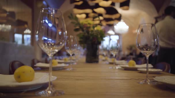 Tablo pahalı bir restoranda servis. Boş şarap gözlük, beyaz tabak, çatal bıçak takımı ahşap bir masa üzerinde. Sulu limon yalan plakaları. — Stok video