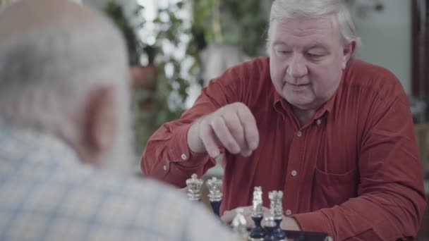 Zwei reife Freunde, die zu Hause Schach spielen. Kaukasische alte Männer, die drinnen fröhlich Schach spielen. Intelligenzherausforderungskonzept — Stockvideo