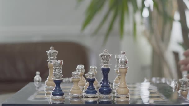 Dois homens a bater os copos com whiskey num tabuleiro de xadrez. O belo conjunto de xadrez com inserções de prata em pé no tabuleiro de xadrez de perto. Conceito de negócio — Vídeo de Stock