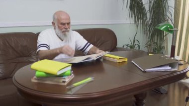 Ahşap masada kitap okuma deri koltukta oturan düşünceli sakallı komuta sizde. Beyaz ihtiyar kapalı zaman zevk. Boş zaman emekli. Eğitim kavramı