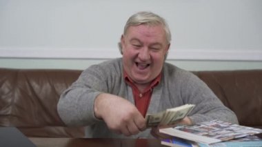 Ahşap masada oturan dolar atmadan mutlu ihtiyar kapatalım. Olumlu zengin adam parasını gösterir. Komik dedesi eve deri kanepede oturan rahatlatıcı. Dinlence