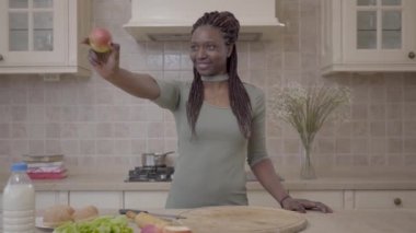 Pasta hazırlama ve gülümseme ile elma seyir emin Afrikalı-Amerikalı genç gülümseyen kadın