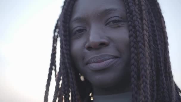 Retrato de mujer joven afroamericana sonriente negra confiada en el fondo del cielo y la calle . — Vídeo de stock