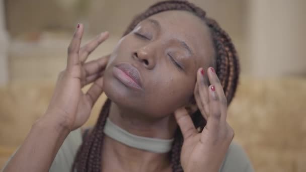 Portrait d'une jolie jeune femme afro-américaine faisant un massage de la tête dans son appartement après une dure journée. Mouvement lent — Video