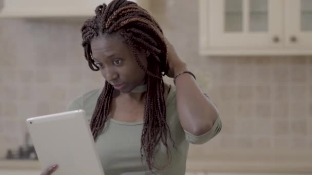 Vrij african american vrouw met dreadlocks verwijdert rubber uit haren en gonna selfie met haar tablet in de keuken nemen. Huisvrouw besteedt tijd thuis — Stockvideo