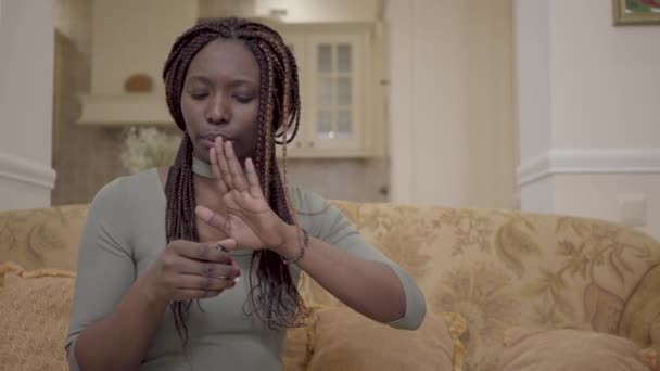 Portrét docela afroamerické ženy dělat červené polský manikúru na trenéra v moderním obývacím pokoji — Stock video