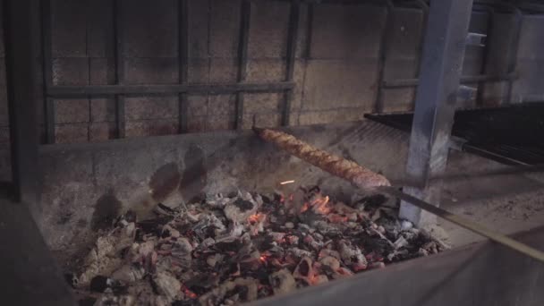 The skewer with tasty lula kebab lying on the grill oven close up. Hand of chef stirs coal using poker to make more heat. Tasty turkish food preparation — Stock Video