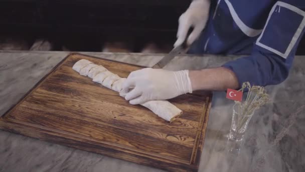 Опытный человек в голубой форме шеф-повара, готовит шашлык в современном турецком ресторане. Повар разрезает кебаб, завернутый в пита-лаваш, большим острым ножом на куски. Турецкая кухня. Вид сверху — стоковое видео