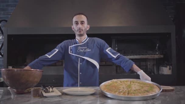 Porträt eines selbstbewussten Erfolgskochs in blauer Uniform, der in der Küche neben einem leckeren, appetitlichen Gericht steht. — Stockvideo