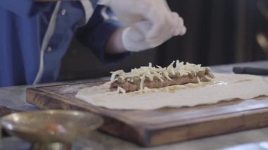 Lula kebap modern Türk restoranında yemek mavi Şef üniformalı tanınmayan yetenekli adam. Haddeleme peynirli kebap ve pide lavaş et sarma kıyılmış Cook kapatıyoruz