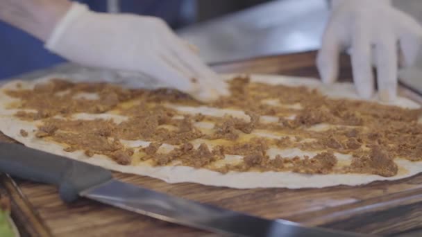 Händerna på mannen i gummihandskar förbereda skålen insvept i lavash närbild. Kocken hand försiktigt sprida pålägg över pita. Turkisk mat — Stockvideo